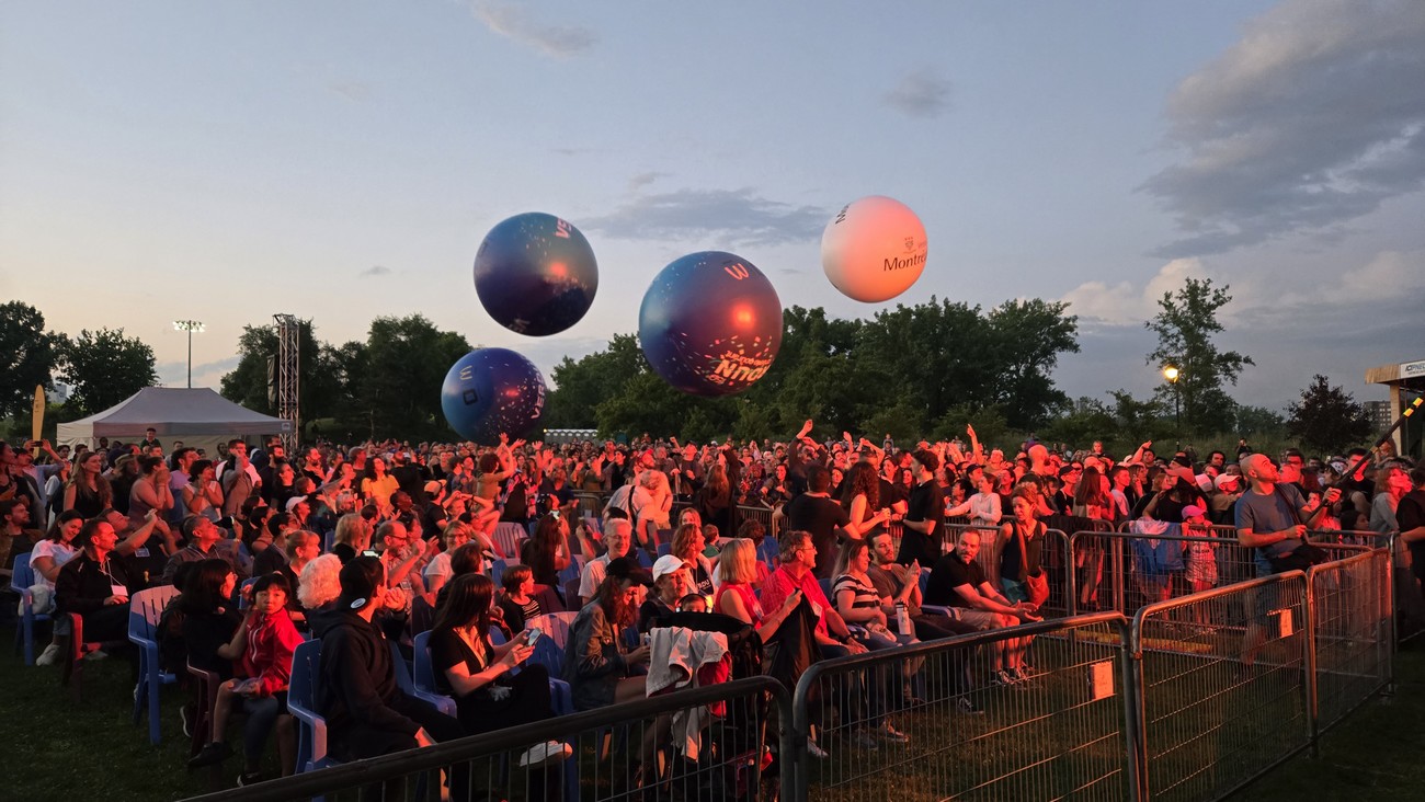 des ballons volent au dessus d'une foule lors d'un concert en plein air
